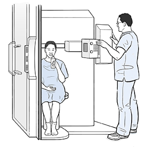 Woman sitting in fluoroscopy scanner sipping liquid through a straw while healthcare provider prepares for scan.